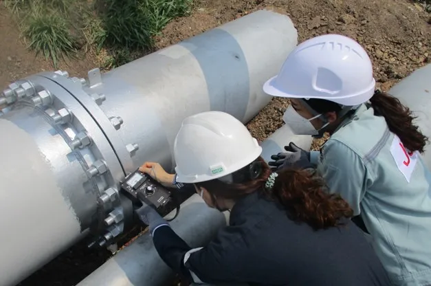 JST technicians taking measurements on exposed pipework